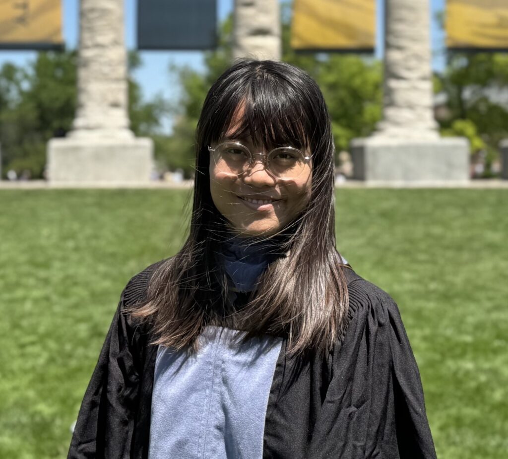 Portrait of Blanca Chen smiling outdoors, with natural light and greenery in the background.